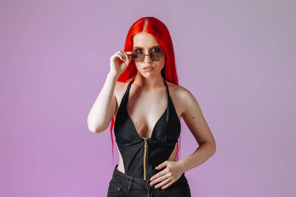 Portrait of a girl with red long hair in round glasses on a pink - Photo, Image