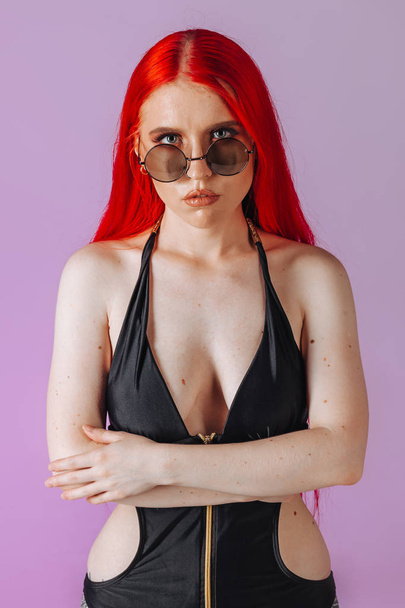 Portrait of a girl with red hair and round glasses on a pink bac - Foto, immagini
