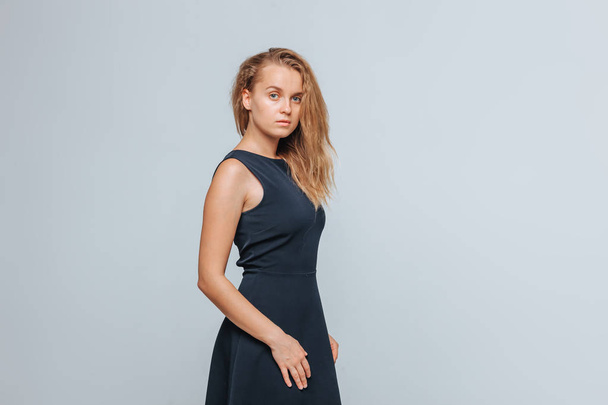 Girl wears blue dress and looks at camera on grey background - Fotoğraf, Görsel