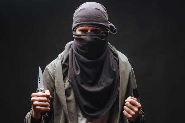  bir maskeli suçlu bir bıçak ile karanlık arka plan tehdit - Fotoğraf, Görsel