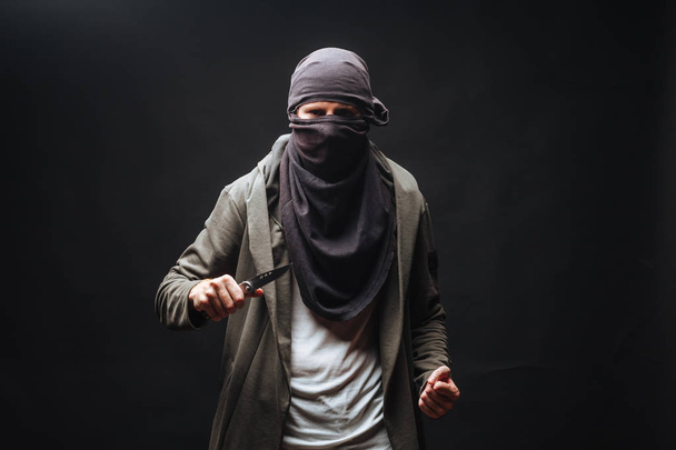  マスクの犯罪者は、暗い背景をナイフで脅す - 写真・画像