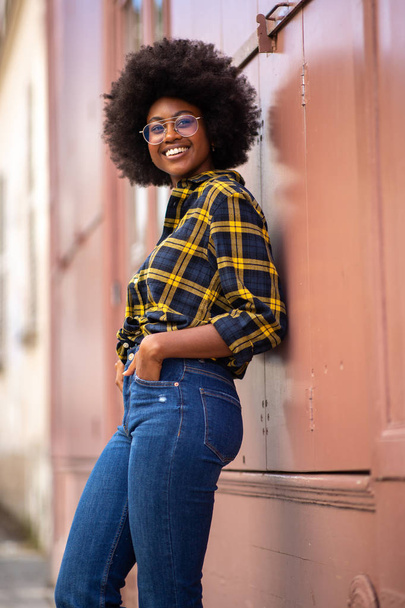 Side portrait smiling young african american woman with afro hair leaning against wall  - Foto, immagini
