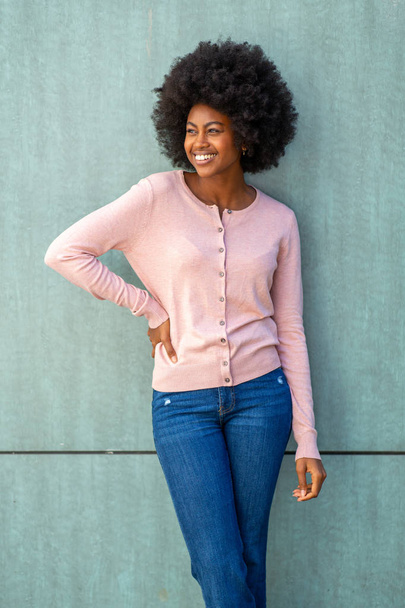 Portret van stijlvolle jonge Afrikaanse Amerikaanse vrouw met afro door groene muur - Foto, afbeelding