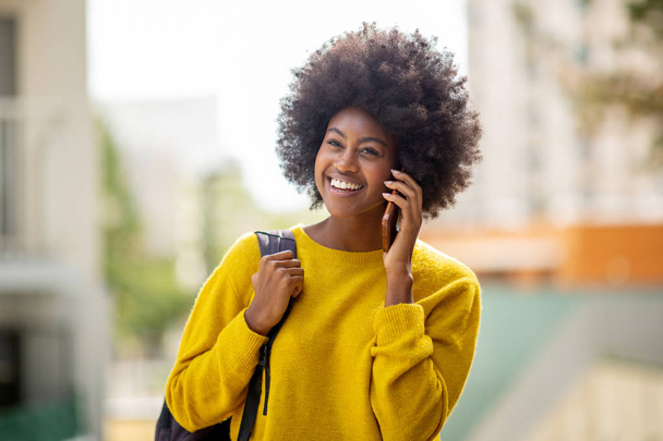Close up portrait of cheerful young black woman talking with cellphone in city - Foto, afbeelding