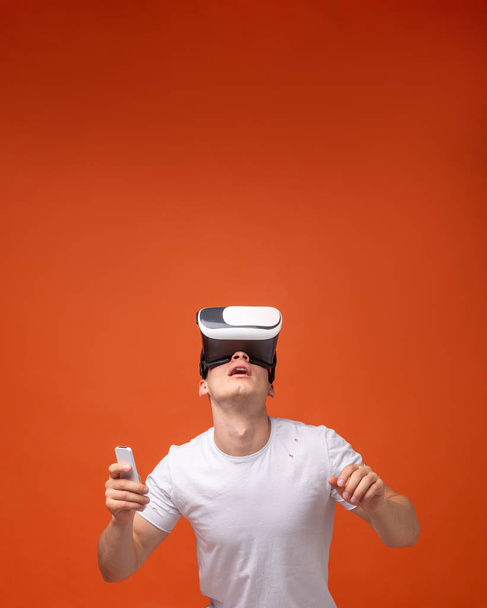 Un hombre en un auricular de realidad virtual mira la parte superior del marco en un lugar para el texto
 - Foto, imagen