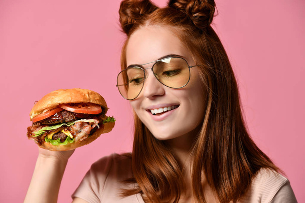 Woman eat burger sandwich with hungry mouth on pink background. - 写真・画像