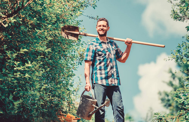 It is time to plant prepare beds and care for lawn. Pick out flats favorite plants. Gardening pro tips. Spring gardening. Man bearded hipster hold shovel and watering can. Spring gardening checklist - Φωτογραφία, εικόνα