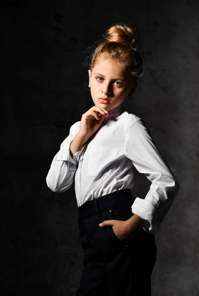 Little female caucasian model posing in school uniform on a gray concrete studio background. - Photo, Image