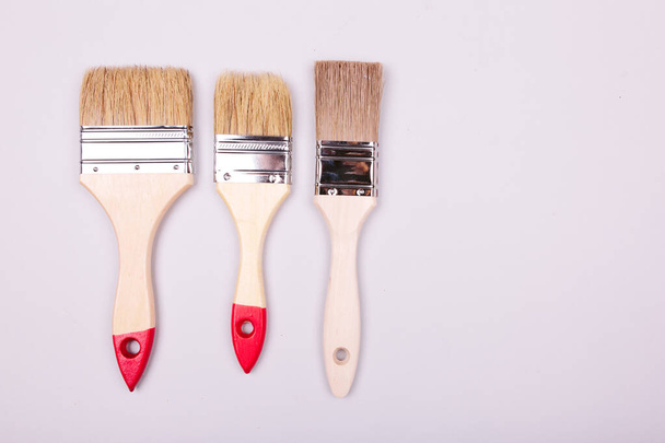 brushes and an open can with red on plain gray background - Photo, image