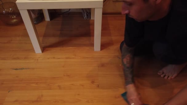 Mladík doma myje podlahu. Detailní záběr na mužskou špínu z dřevěné podlahy se speciálním hadříkem. - Záběry, video
