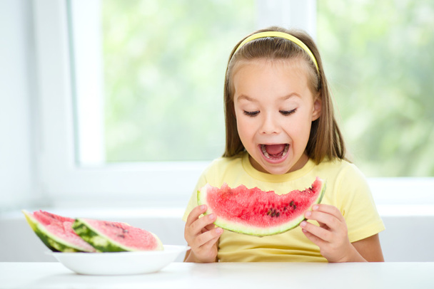 Cute little girl is eating watermelon - Fotoğraf, Görsel