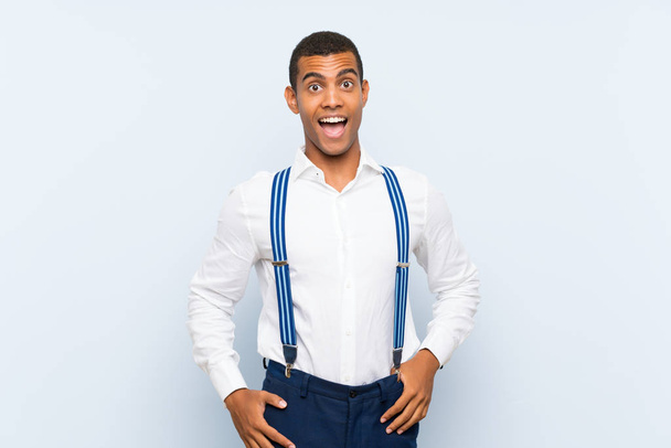 Young handsome brunette man with suspenders over isolated background with surprise facial expression - Fotó, kép