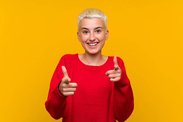 Teenager girl with white short hair over yellow wall points finger at you - Foto, Imagen