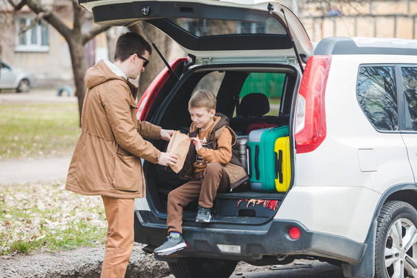 father with son packing bags to car trunk. car travel concept - Photo, Image