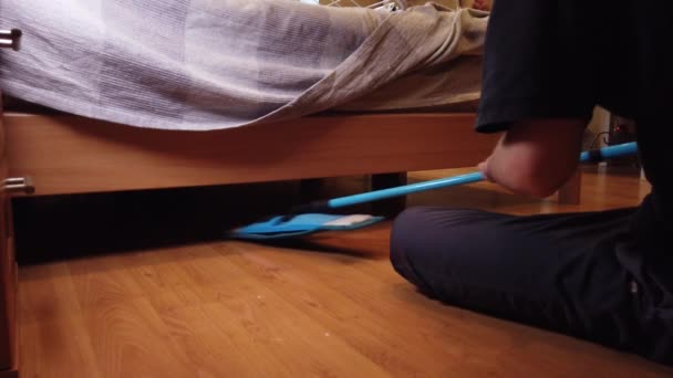 Mladík doma myje podlahu. Detailní záběr na mužskou špínu z dřevěné podlahy se speciálním hadříkem. - Záběry, video