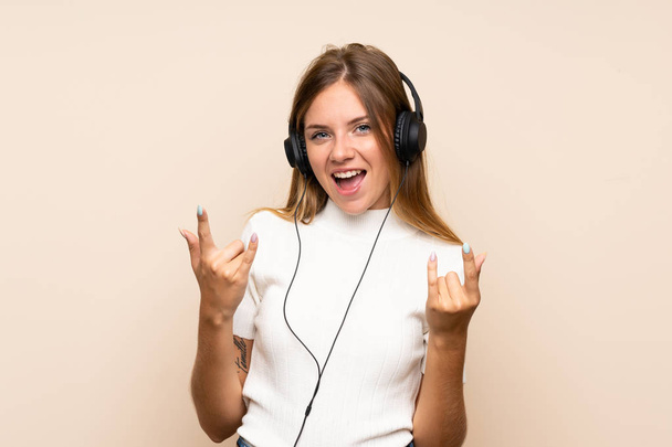 junge blonde Frau über isolierten Hintergrund mit dem Handy mit Kopfhörern und Tanzen - Foto, Bild