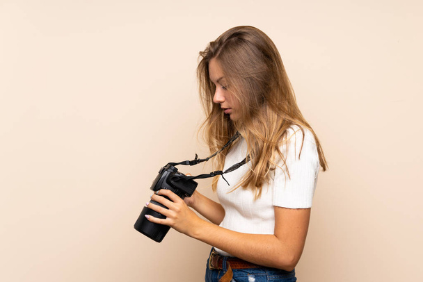 jong blond vrouw over geïsoleerde achtergrond met een professionele camera - Foto, afbeelding