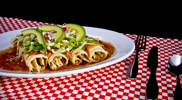 Enchilada rouge avec tranches d'avocat et fromage émietté
 - Photo, image