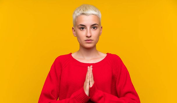 Teenager dívka s bílými krátkými vlasy přes žlutou zeď prosí - Fotografie, Obrázek