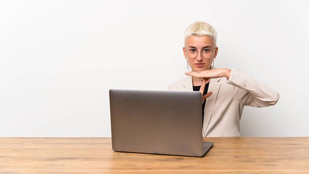 Adolescente chica con el pelo corto con un ordenador portátil haciendo tiempo de espera gesto
 - Foto, imagen