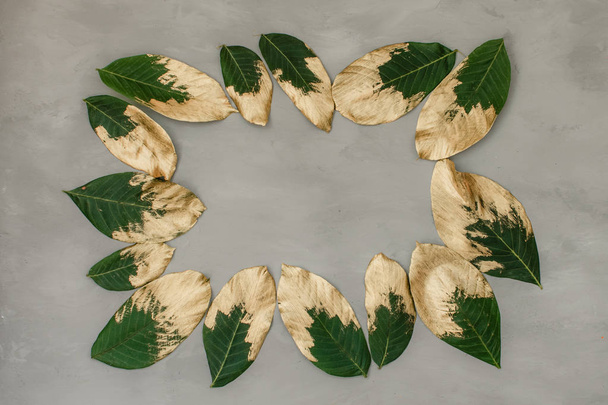Creative nature background. Gold and green painted leaves on gra - Photo, Image