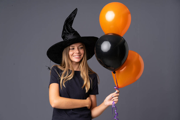 Jovem bruxa segurando balões de ar preto e laranja rindo - Foto, Imagem