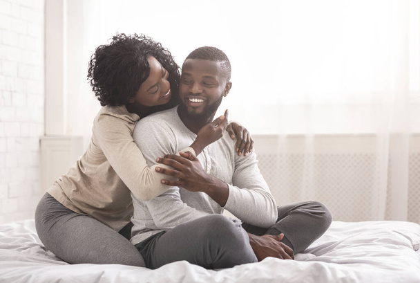 Ρομαντικό ζευγάρι χιλιετιών αγκαλιάζει ενώ κάθεται στο κρεβάτι το πρωί - Φωτογραφία, εικόνα