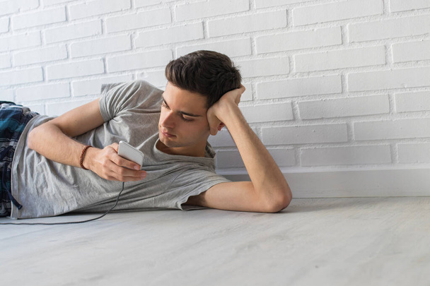 young man or teenager with mobile phone at home - Photo, Image