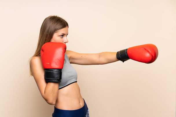 Young blonde girl with boxing gloves over isolated background - 写真・画像