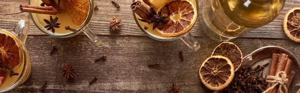 木の素朴なテーブルにスパイスと乾燥した柑橘類と伝統的な暖かい梨のマルチワインのトップビュー,パノラマショット - 写真・画像