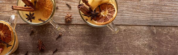 top view of warm pear mulled wine with spices and dried citrus on wooden rustic table, panoramic shot - Photo, Image