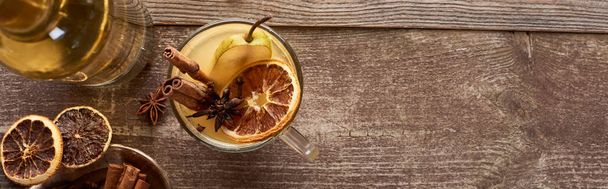 top view of warm pear mulled wine with spices and dried citrus on wooden rustic table, panoramic shot - Valokuva, kuva