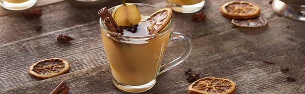 pear mulled wine with spices and dried citrus on wooden table, panoramic shot - Foto, Imagem