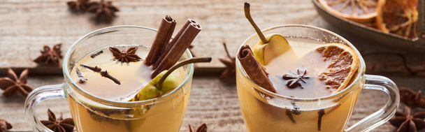 pear mulled wine with spices and dried citrus on wooden table, panoramic shot - 写真・画像