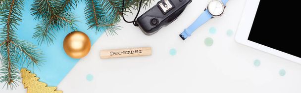 panoramatický záběr digitální tablety, jedlové větve, náramkové hodinky, vánoční ozdoby, dřevěný blok s prosincovým nápisem izolovaný na bílém - Fotografie, Obrázek