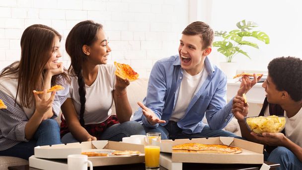 Adolescentes emocionados comiendo pizza y hablando en casa
 - Foto, imagen