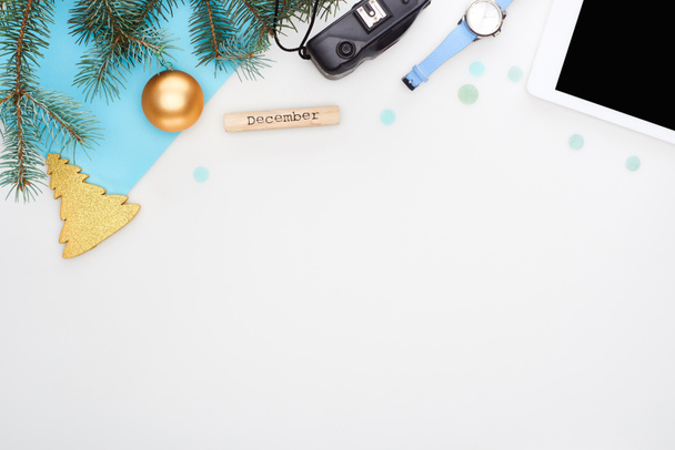цифровая камера, еловая ветвь, рождественские безделушки, цифровая табличка, деревянный блок с сентябрьской надписью, голубая бумага, изолированная на белом
 - Фото, изображение