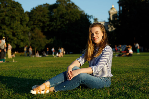 Portrait of a cute girl in the city. girl on the lawn in a city park - Foto, Imagem
