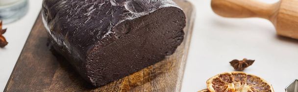 panoramic shot of raw dough on wooden cutting board near anise and dried fruits - Foto, immagini
