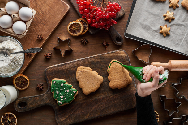 cropped view of woman glazing Christmas cookies on wooden table - Photo, Image