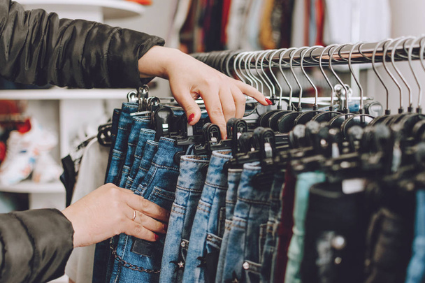 Быстрая мода. Женщина выбирает джинсы в магазине. Много cl
 - Фото, изображение