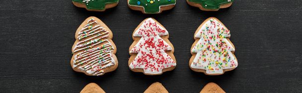 flat lay with delicious glazed Christmas tree cookies on black background, panoramic shot - Foto, Imagem
