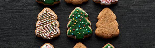 flat lay with delicious glazed Christmas tree cookies on black background, panoramic shot - Zdjęcie, obraz