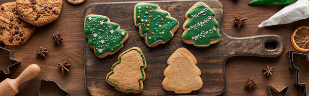 vista superior de galletas de Navidad acristaladas con bolsa de repostería en tabla de cortar de madera, plano panorámico
 - Foto, Imagen