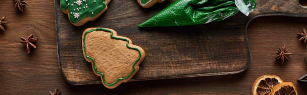 vue de dessus des biscuits de sapin de Noël, sac à pâtisserie et épices d'hiver sur table en bois, vue panoramique
 - Photo, image