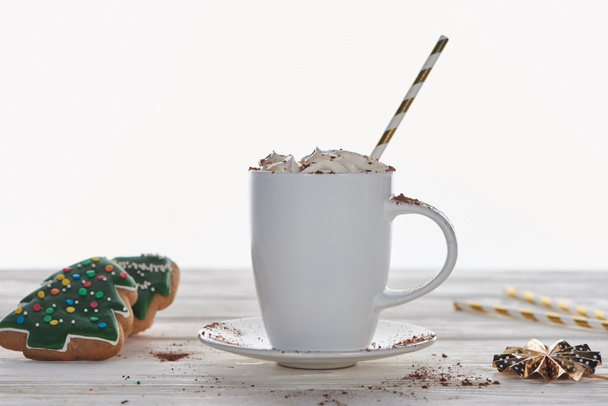 Cacao de Navidad con crema batida y paja en taza cerca de galletas en mesa de madera aislada en blanco
 - Foto, Imagen