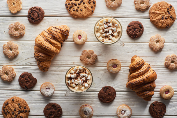 top view of cacao with marshmallow near cookies and croissants on white wooden table - Fotografie, Obrázek