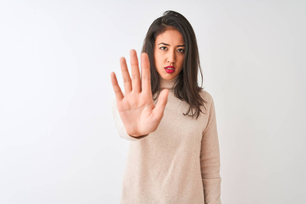 Beautiful chinese woman wearing turtleneck sweater standing over isolated white background doing stop sing with palm of the hand. Warning expression with negative and serious gesture on the face. - Photo, Image