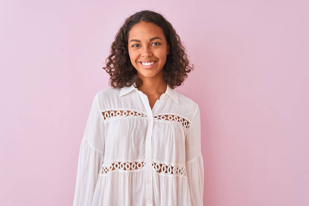 Young brazilian woman wearing shirt standing over isolated pink background with a happy and cool smile on face. Lucky person. - Photo, Image