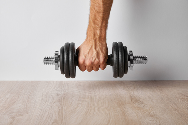 cropped view of sportsman holding dumbbell on white  - Fotoğraf, Görsel